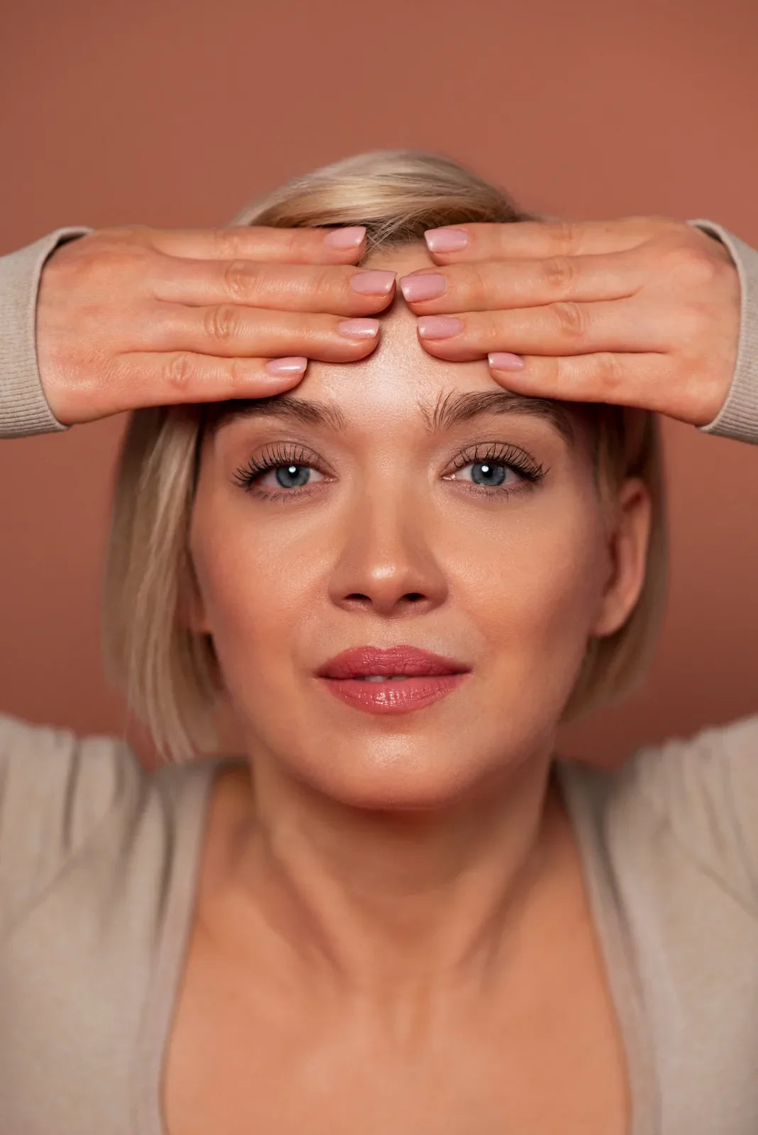 Woman in her forties smoothing her forehead outward with the fingertips of both hands