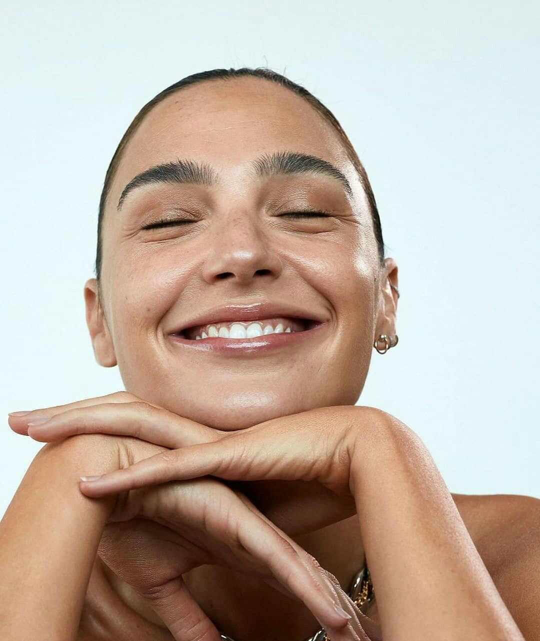 Smiling woman with glowing skin resting her chin on her hands