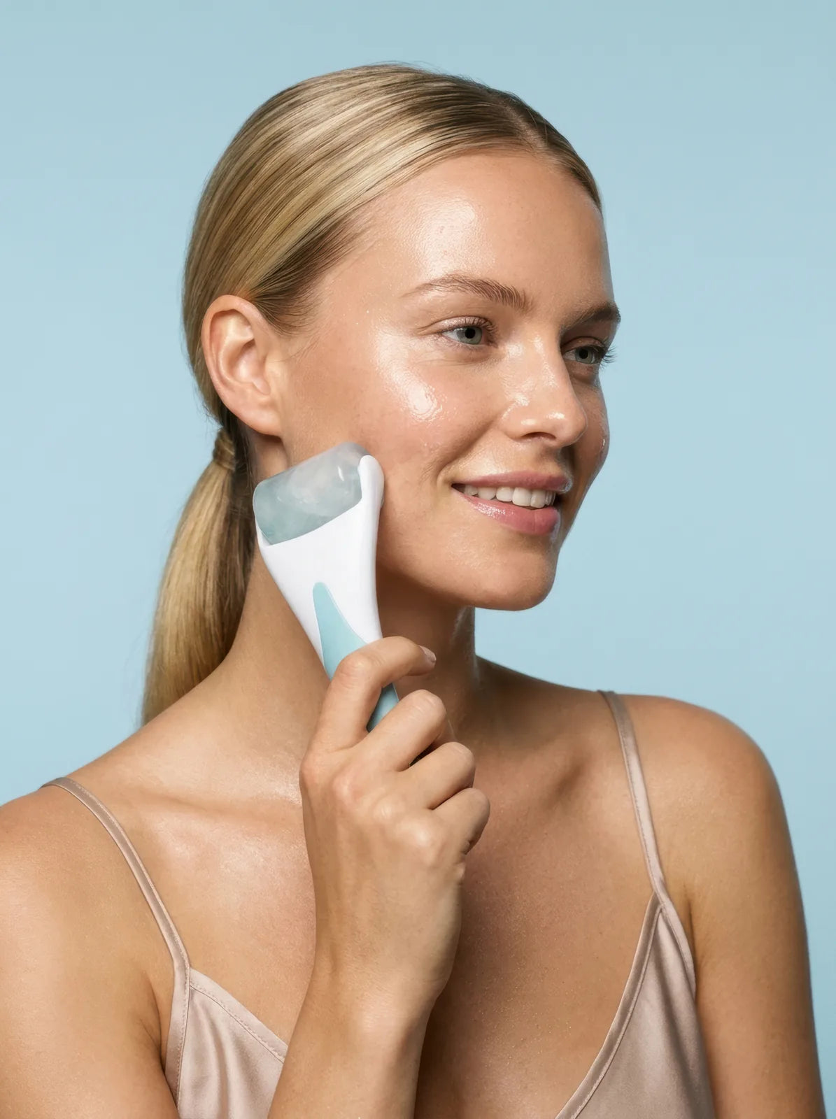 Woman gliding a cooled facial roller along her cheek for a cold finish
